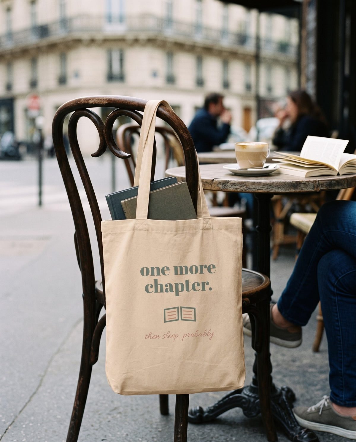 One More Chapter Tote, hanging on a cafe chair with books inside