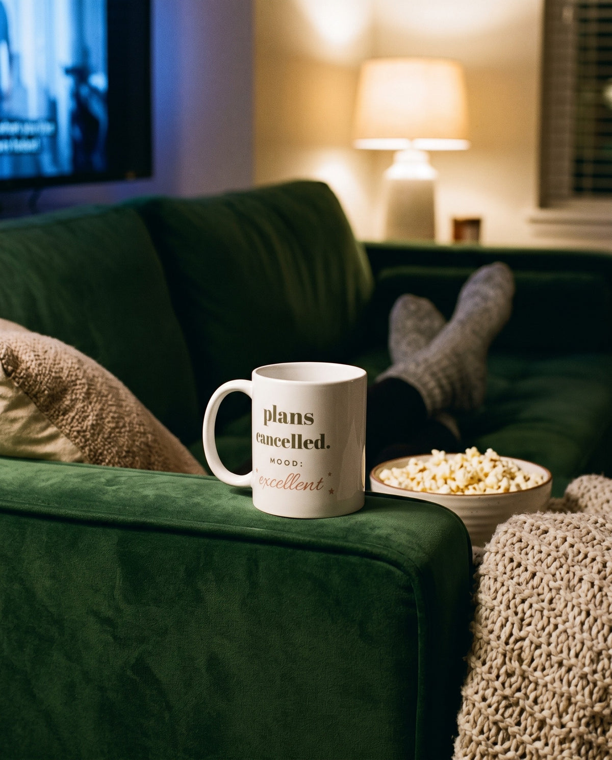 Plans Cancelled Mug, on the arm of a green sofa with popcorn