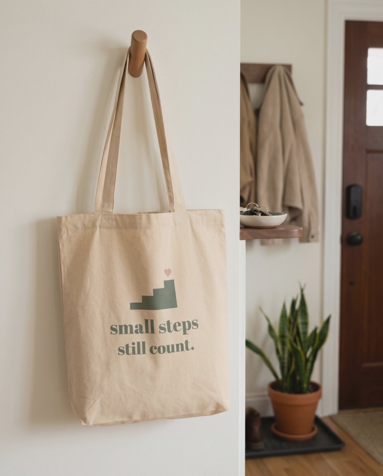 Small Steps Still Count Tote, a short clip of it hanging on a hallway peg in soft daylight