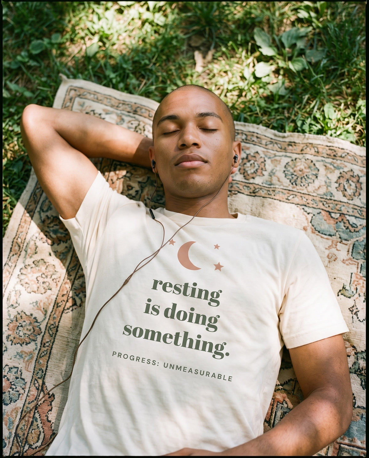 Resting Is Doing Something Tee, worn lying on a blanket in the park