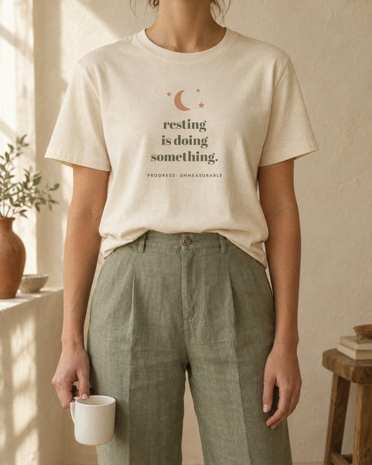 Resting Is Doing Something Tee, in soft cream, worn with sage linen trousers