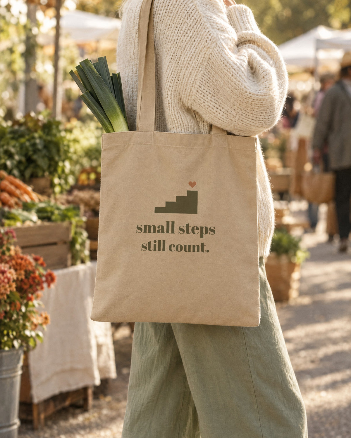 Small Steps Still Count Tote, in natural oyster, carried on the shoulder at a market