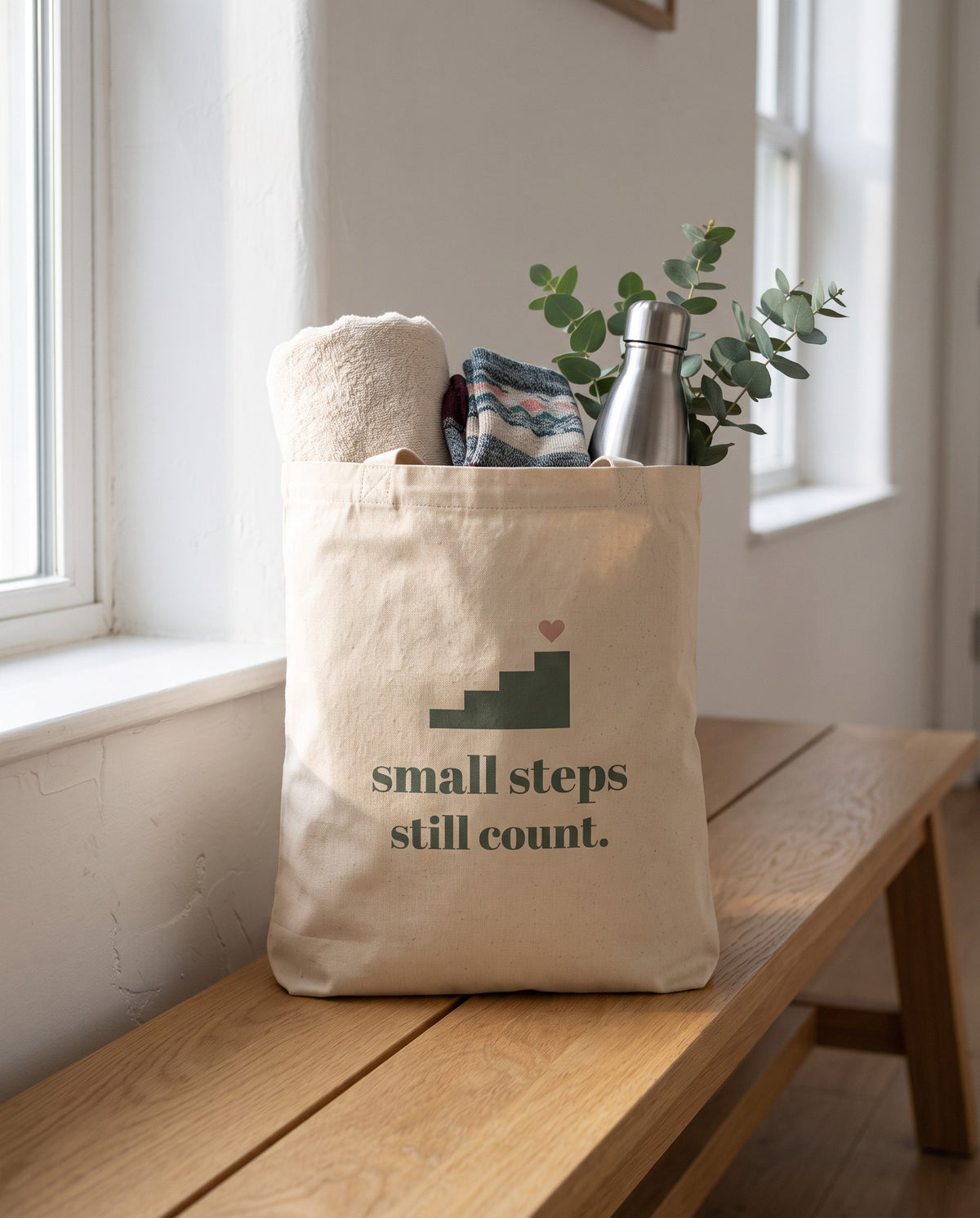 Small Steps Still Count Tote, packed with a towel, socks, a water bottle and eucalyptus