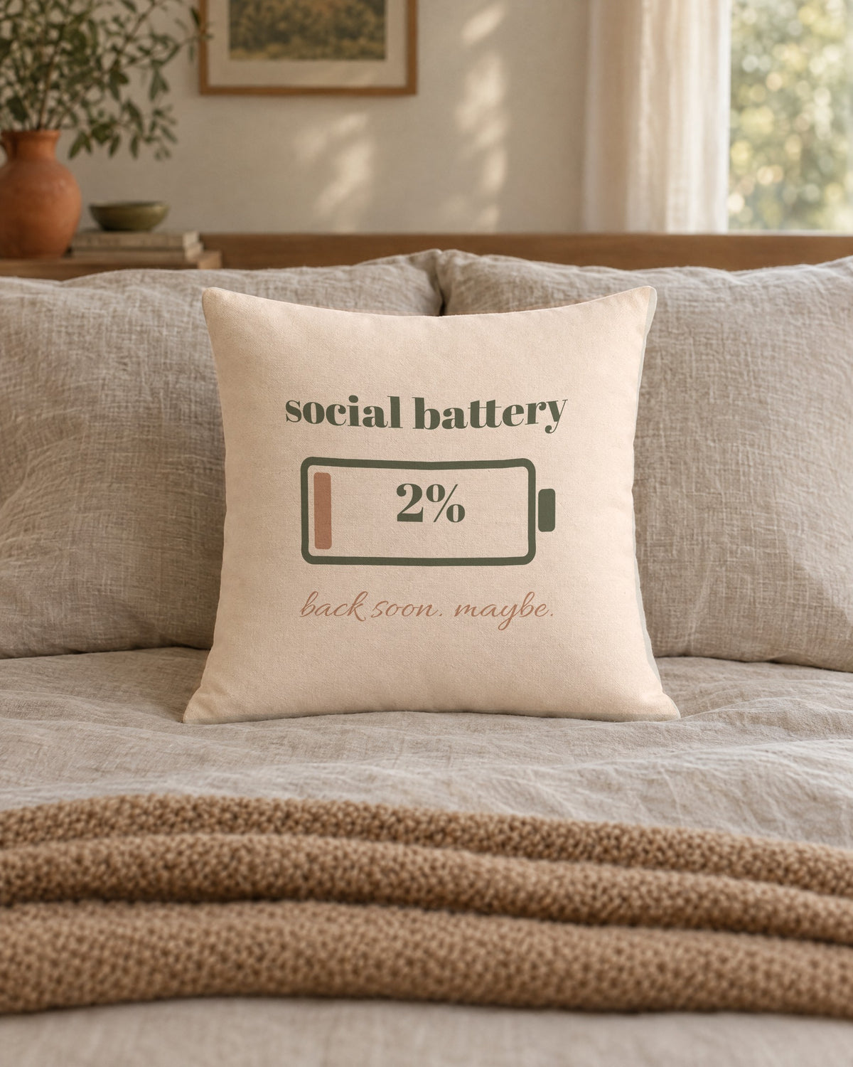 Social Battery Pillow, 18 x 18 in, on a made bed