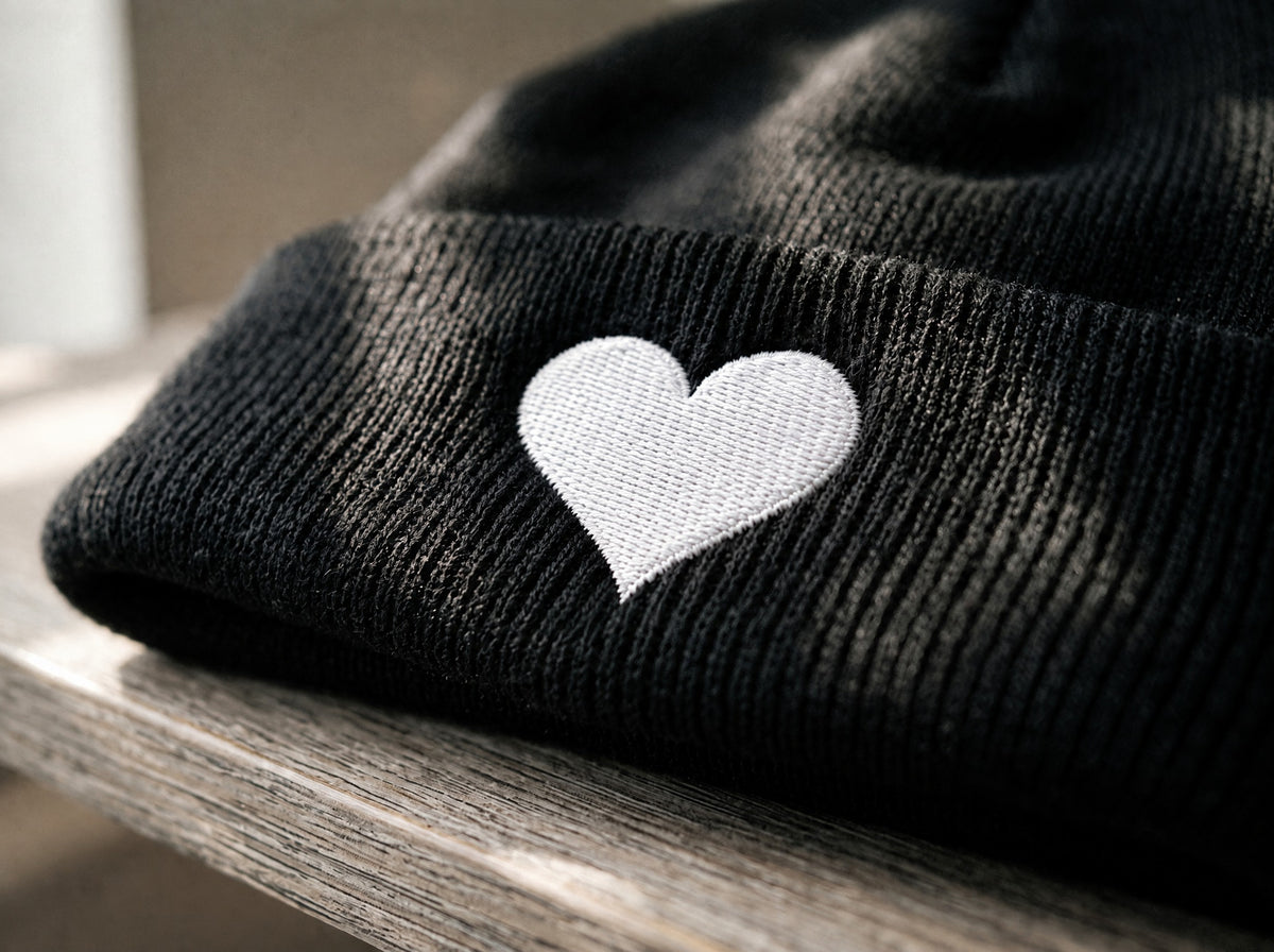 Soft Heart Beanie, the embroidery up close on the black cuff: a small white heart.