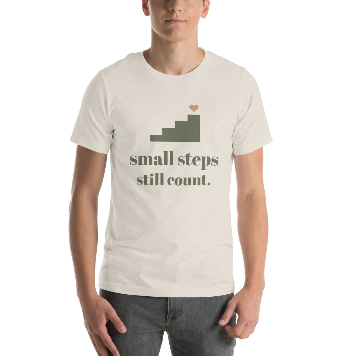 Small Steps Still Count Tee in Heather Dust, worn by a model, front print: a small staircase with a heart, small steps still count